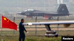 A China-made J-31 stealth fighter (background) lands on a runway after a flying performance at the China International Aviation and Aerospace Exhibition in Zhuhai, Guangdong province, Nov. 11, 2014.