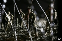 U.S. Border Patrol agents stand on the U.S. side of the border, seen through the concertina wire where the border meets the Pacific Ocean, Thursday, Nov. 15, 2018, from Tijuana, Mexico.