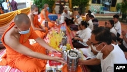 People offer food to Buddhist monks during the Pchum Ben festival (Festival of Death) at a pagoda in Phnom Penh on September 3, 2020. (Photo by TANG CHHIN Sothy / AFP)