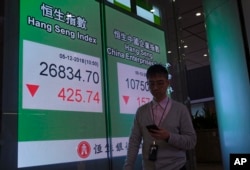 A man walks past an electronic board showing Hong Kong share index outside a local bank in Hong Kong, Dec. 5, 2018.