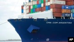 Miembros de la tripulación del CMA CGM Argentina, el barco carguero más grande en hacer escala en el Puerto de Miami, miran desde la proa el 6 de abril de 2021.