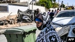 Los autos destruidos en un ataque con cohetes supuestamente disparados desde la Franja de Gaza se ven a través de una ventana dañada de una casa en la aldea de Arara, en el desierto de Negev, el 14 de octubre de 2023.