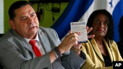 FILE - Francisco Portillo, left, president of the Honduran organization Francisco Morazan, holds up a postcard addressed to President Donald Trump asking to extend Temporary Protected Status for Central Americans and Haitians. He and Marleine Bastien, of Haitian Women of Miami, speak at a news conference in Miami, June 7, 2017.