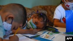 Los niños asisten a clase en un aula improvisada en una casa en el barrio de Petare, el barrio marginal más grande de Venezuela, en Caracas en medio de la pandemia del nuevo coronavirus COVID-19, el 16 de septiembre de 2020.