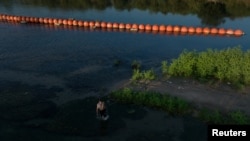 Un contrabandista, usualmente llamado 'coyote', pasa junto a boyas desplegadas para disuadir a los migrantes en el río Grande entre Estados Unidos y México, en Eagle Pass, Texas, EEUU, el 14 de septiembre de 2023.