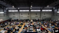 Ukrainian refugees wait in a gymnasium Tuesday, April 5, 2022, in Tijuana, Mexico. (AP Photo/Gregory Bull)