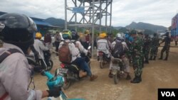 Personel TNI-POLRI melakukan pemeriksaan terhadap pekerja yang hendak memasuki pabrik smelter PT GNI di Morowali Utara, Sulawesi Tengah, 19 Januari 2023 menyusul terjadinya bentrok antara pekerja Indonesia dan China. (Foto : VOA/Yoanes Litha)