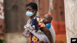 A woman carries her son, who has cholera, at Bwaila Hospital in Lilongwe central Malawi, Wednesday, Jan. 11, 2023. Malawi's health minister says the country's worst cholera outbreak in two decades has killed 750 people so far.