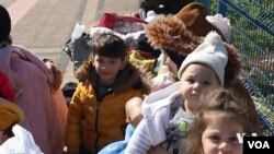 خێزانێکی سوریایی پاش بوومەلەرزەکەی تورکیا لەسەر شقامێکی مێرسین