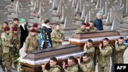 Wanajeshi wabeba majeneza wakati wa maziko ya Dmytro Kotenko, Vasyl Vyshyvany na Kyrylo Moroz, wanajeshi wa Ukraine waliouawa wakati wa uvamizi wa Russia nchini Ukraine, katika makaburi ya Lychakiv magharibi ya mji wa Lviv, March 9, 2022. Picha naYuriy Dyachyshyn / AFP)