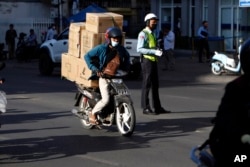 រូបឯកសារ៖ បុរសម្នាក់ដឹកទំនិញតាមម៉ូតូជូនអតិថិជន នៅភ្នំពេញ ថ្ងៃទី ១៩ ខែមករា ឆ្នាំ ២០២២។