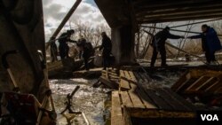 Civilians in Irpin escape from the battles through an improvised path created alongside a bombed bridge by Ukrainian forces in Ukraine, March 8, 2022. (Yan Boechat/VOA) 