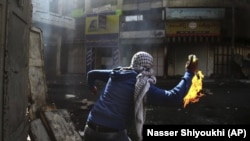FILE - A Palestinian protester throws a Molotov cocktail towards Israeli soldiers during conflicts in the West Bank city of Hebron, April 3, 2013. (AP Photo/Nasser Shiyoukhi, File)