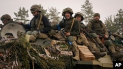 Ukrainian servicemen ride on an armored transporter moving through a Russian position that had been overrun by Ukrainian forces outside Kyiv, Ukraine, March 31, 2022.