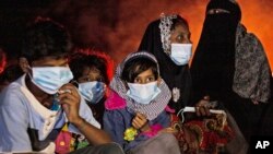 Ethnic Rohingya women and children sit by a fire on a beach after their boat was stranded on Idaman Island in East Aceh, Indonesia, late Friday, June 4, 2021, after leaving a refugee camp in Bangladesh, officials said. (AP Photo/Zik Maulana)