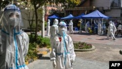 បុគ្គលិក​សុខាភិបាល និង​អ្នក​ធ្វើការ​ស្ម័គ្រចិត្ត​មួយ​ចំនួន​ធ្វើ​តេស្ត​រក​ជំងឺ​កូវីដ១៩​ដល់​អ្នក​រស់នៅ​ក្នុង​អគារ​ស្នាក់នៅ​មួយ​កន្លែង​ក្នុង​ទីក្រុង​សៀងហៃ ប្រទេស​ចិន ថ្ងៃទី៤ ខែមេសា ឆ្នាំ២០២២។ (AFP) 