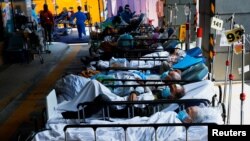 FILE - Patients wearing face masks rest at a makeshift treatment area outside a hospital, following the COVID-19 outbreak in Hong Kong, China, March 2, 2022.