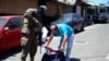 Un miembro del ejército revisa los documentos y pertenencias de un hombre en plena calle durante un patrullaje después de que el Congreso de El Salvador aprobara el domingo poderes de emergencia que suspendieron temporalmente algunas protecciones constitucionales.