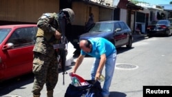 Un miembro del ejército revisa los documentos y pertenencias de un hombre en plena calle durante un patrullaje después de que el Congreso de El Salvador aprobara el domingo poderes de emergencia que suspendieron temporalmente algunas protecciones constitucionales.