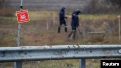 Expertos ucranianos buscan artefactos explosivos sin detonar y minas terrestres junto a la carretera principal a Jersón, Ucrania, el 16 de noviembre de 2022.