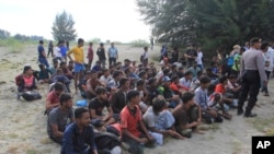 Ethnic Rohingya people sit on a beach after they landed in Aceh Besar, Indonesia, Sunday, Jan. 8, 2023. A group of Rohingya Muslims who sailed on a wooden boat landed in Indonesia's northernmost province of Aceh on Sunday. (AP Photo/Irwandi)