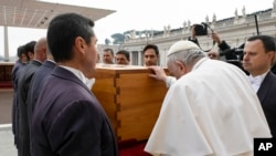 In this image released by the Vatican Media news service, Pope Francis touches the coffin of late Pope Emeritus Benedict XVI after his funeral mass in St. Peter's Square at the Vatican, Jan. 5, 2023.