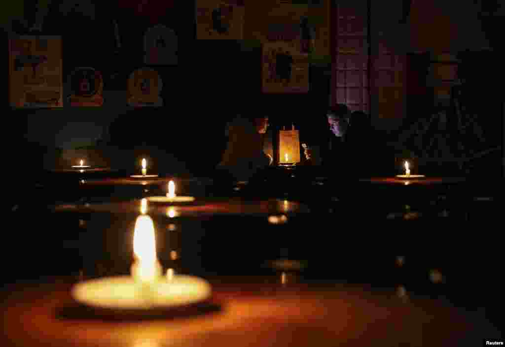 People sit in a pub lit with candles during a power outage after critical civil infrastructure was hit by Russian missile attacks, as Russia's invasion of Ukraine continues, in Lviv, Ukraine Nov. 24, 2022.
