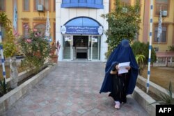 A female university Student walks in front of a university in Kandahar Province on December 21, 2022. - Afghanistan's Taliban rulers have banned university education for women nationwide, provoking condemnation from the United States and the United Nations over another assault on human rights. (Photo by STRINGER / AFP)