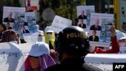 FILE - A police officer blocks workers from the NagaWorld casino holding placards during a protest outside the National Assembly building after several union members were arrested, in Phnom Penh, Jan. 4, 2022.