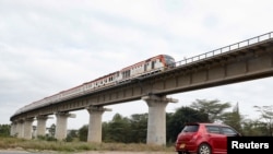 Gari dogo likipinda chini ya daraja huku gari moshi likipita kwenye reli ya mwendo wa wastani SGR, Athi River, Kenya. June 3, 2022
