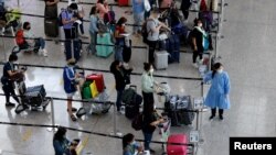 FILE - Travelers queue up for shuttle bus to quarantine hotels at the Hong Kong International Airport, amid the coronavirus disease (COVID-19) pandemic, August 1, 2022. 