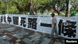 资料照：一名男子走过台北街头悬挂的写有“投资中国死路一条”字样的标语。（2012年8月8日）