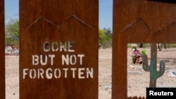Las tumbas se ven a través de los recortes de un letrero que dice "ido pero no olvidado" y un cactus saguaro en el cementerio del condado de Pima, ubicado dentro del cementerio Evergreen en Tucson, Arizona, el 9 de mayo de 2022. REUTERS/Rebecca Noble/Foto de archivo