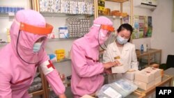 FILE - This picture taken and released from North Korea's official Korean Central News Agency (KCNA) on May 31, 2022 shows Korean People's Army medical personnel in protective clothing supplying medicines at a pharmacy in Pyongyang. (Photo by KCNA VIA KNS