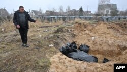 បុរស​ម្នាក់​ឈរ​មើល​រណ្ដៅ​សព​ធំ​មួយ​នៅ​ក្នុង​ក្រុង Bucha ដែល​ស្ថិត​នៅ​ជាយ​រដ្ឋធានី​កៀវ ប្រទេស​អ៊ុយក្រែន ថ្ងៃទី៣​ ខែមេសា ឆ្នាំ២០២២។ (Photo by Sergei SUPINSKY / AFP)