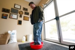 Ryan Bickel walks through a shoe disinfectant as he enters a building at the Blank Park Zoo, April 5, 2022, in Des Moines, Iowa. Zoos across North America are moving their birds indoors and away from people and wildlife as they try to protect them from av