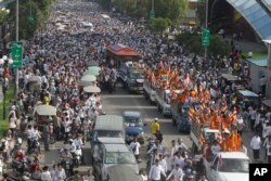 Mourners follow the body of Cambodian leading government critic Kem Ley in a glass casket carried on a decorated vehicle, top, on the main street during a funeral procession at Chroy Changvar in Phnom Penh, Cambodia, July 24, 2016.