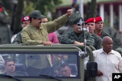 FILE - Defense Minister Vladimir Padrino Lopez, center right, face obscured, and Gen. Ivan Hernández, standing behind Padrino Lopez, head of both the presidential guard and military counterintelligence, accompany Venezuela's President Nicolas Maduro as they arrive in Caracas, Venezuela, April 13, 2018.