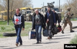 Civilians who left the area near Azovstal steel plant in Mariupol walk accompanied by a member of the International Committee of the Red Cross (ICRC) at a temporary accommodation center in the village of Bezimenne in the Donetsk Region, Ukraine, May 1, 20