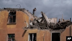 A firefighter works to extinguish a fire as he looks for potential victims after a Russian attack that damaged a residential building in Sloviansk, Ukraine, Sept. 7, 2022.