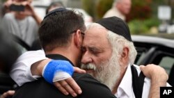 Kasisi Yisroel Goldstein, kulia, akifarijiwa na waumini wakati akiondoka kutoka katika mkutano wa waandishi wa habari huko Chabad, katika Sinagogi la Poway Jumapili, Aprili 28, 2019