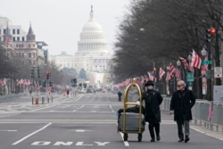 Danish Rozario, left, of Silver Spring, Md., wheels baggage down Pennsylvania Avenue for a guest at the Trump Hotel in Washington, Friday, Jan. 15, 2021, ahead of the inauguration of Joe Biden. (AP Photo/Susan Walsh)