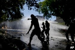 Protesters throwing stones at police are sprayed by water cannons during a general strike against a pension reform measure, outside Congress in Buenos Aires, Argentina, Dec. 18, 2017.