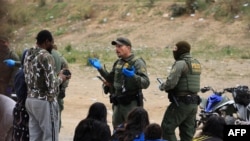 Agentes de la Patrulla Fronteriza de Estados Unidos procesan a migrantes entre las vallas primaria y secundaria de la frontera entre México y Estados Unidos en San Diego, California, el 22 de septiembre de 2023. [AFP/David Swanson]