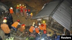 Firefighters rescue people from a house following a landslide in Chittagong, Bangladesh, June 26, 2012.