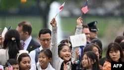 Deca mašu američkim i japanskim zastavama uoči dolaska japanskog premijera u Belu kuću ( ANDREW CABALLERO-REYNOLDS / AFP)