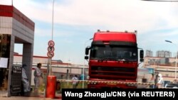 中國發現非洲豬瘟後，河南省鄭州肉類加工企業雙匯集團大門處可以看到身著防護服的工人。（2018年8月17日）