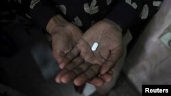 FILE - An AIDS patient holds an anti-retroviral drug used to treat HIV/AIDS.