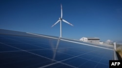 FILE - A solar panel installation is seen near a wind turbine at the Phu Lac wind farm in southern Vietnam's Binh Thuan province, April 23, 2019. 