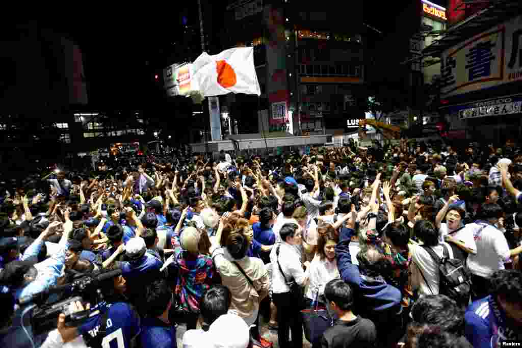 Soccer fans and pedestrians exchange high fives to praise Japan's soccer team players near a diagonal crosswalk after World Cup Group H soccer match Japan vs Senegal, at Shibuya district in Tokyo, Japan.